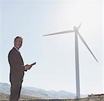 Businessman admiring wind turbine in rural landscape