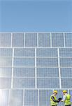 Workers examining solar panels in rural landscape