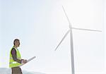 Worker standing by wind turbine in rural landscape