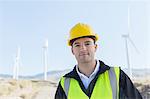 Worker standing by wind turbines in rural landscape