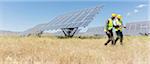 Workers walking by solar panels in rural landscape