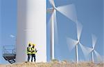 Workers talking by wind turbines in rural landscape