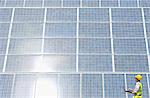 Worker examining solar panel in rural landscape