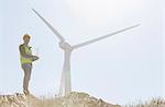 Worker standing by wind turbine in rural landscape