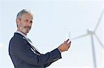 Businessman with glass of water by wind turbine