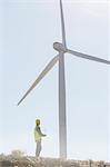 Businessman examining wind turbine in rural landscape