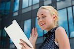 Young woman waving at digital tablet