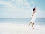 Woman standing on one leg on beach, side view