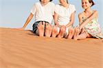 Children sitting on sand dune