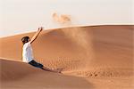 Teenage boy playfully tossing sand into air