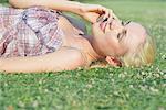 Young woman lying on grass, talking on cell phone