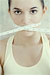 Woman with measuring tape wrapped across mouth