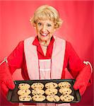 Sweet pretty grandmother holding a tray of freshly baked chocolate chip cookies.