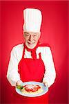 Handsome Italian chef cooks spaghetti marinara.  Red background.