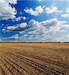 ploughed field under deep blue sky with clouds