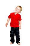 Young boy wearing jeans and a red T-shirt stood isolated on a white background smiling looking into the camera