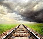 Railway in the field and storm clouds