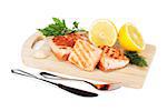 Grilled salmon with lemon and herbs on cutting board and silverware. Isolated on white background