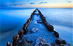 old wooden breakwater in North sea in dusk