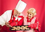 Housewife proudly shows off a fresh batch of chocolate chip cookies to a chef.
