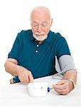 Senior man checking his blood pressure at home.  Isolated on white.