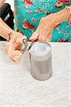 Closeup of senior woman's hands as she struggles to open a can with her painful arthritis.