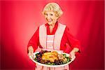 Sweet grandmother holding a beautifully cooked turkey dinner.