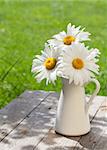 Fresh garden chamomile bouquet in vase on wooden table