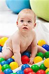 Baby boy playing with colorful plastic balls on the floor - closeup