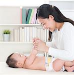 Asian mother playing with baby girl at home.