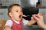 Mother feeding baby girl, baby opens mouth wide