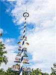 Picture of a typical traditional bavarian maypole with blue sky and white clouds
