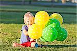 smiling adorable boy with colorful balloons outside