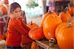 Cute Girl Choosing A Pumpkin at A Pumpkin Patch One Fall Day.