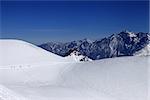 Snowboarders move on footpath to off piste slope at sun day. Caucasus Mountains, Georgia, ski resort Gudauri.