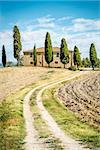 landscape in tuscany, italy with house, fields, cypresses and blue sky