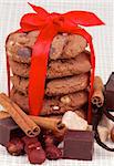 Arrangement of Delicious Christmas Cookies Tied with Red Ribbon and Chocolate, Nuts, Cinnamon Sticks and  Sugar Cubes closeup on Checkered background