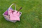 Woven basket of knitting, wooden needles and soft yarn on green grass