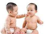 Two Asian babies having baby talk, sitting isolated over white background.