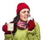 Sick Mixed Race Woman Wearing Winter Hat and Gloves Blowing Her Sore Nose and Holding Cup of Hot Tea Isolated on White.