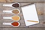 Colorful herbs and spices selection. Aromatic ingredients on wood table with blank notepad copyspace