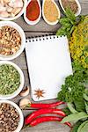 Colorful herbs and spices selection. Aromatic ingredients on wood table with blank notepad