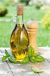 Olive oil bottle, pepper shaker and basil on wooden table