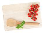 Cooking utensil and tomato with basil over cutting board. Isolated on white background