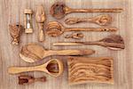 Olive wood  products and kitchen utensil selection over papyrus background.