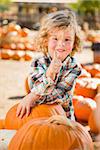 Adorable Little Boy Leaning on Pumpkin Gives a Thumbs Up in a Rustic Ranch Setting at the Pumpkin Patch.