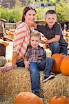 Attractive Mother and Her Two Sons Pose for a Portrait in a Rustic Ranch Setting at the Pumpkin Patch.