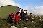 Young people camping in the mountains in the evening