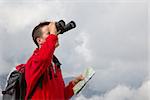 Young hiker is searching the destination while hiking above the clouds