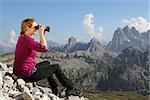 Young woman looking through binoculars in the mountains